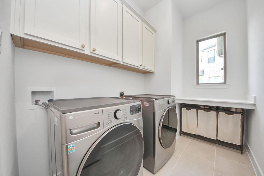 Spacious laundry room with modern appliances, ample cabinetry, and natural light from a large window.