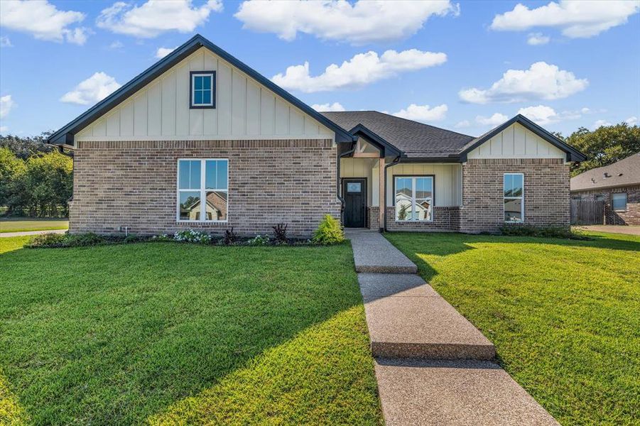 View of front facade with board and batten siding, a front lawn, and brick siding View of front facade with board and batten siding, a front lawn, and brick siding