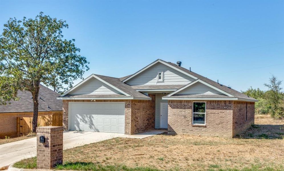 Ranch-style house featuring concrete driveway, brick siding, a garage, and a shingled roof