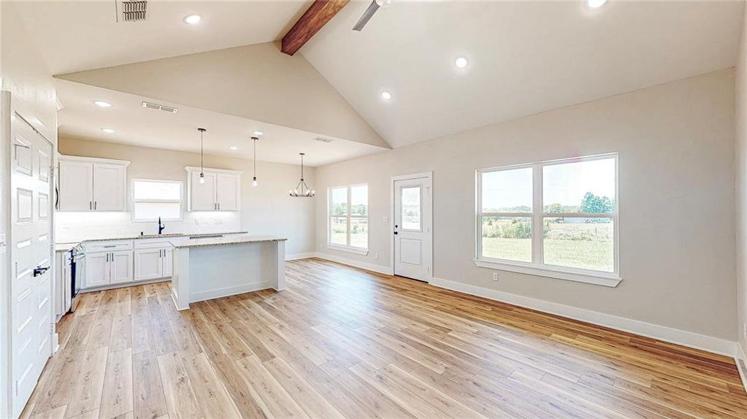Kitchen featuring beam ceiling, a kitchen island, light wood-style floors, recessed lighting, and white cabinetry Kitchen featuring beam ceiling, a kitchen island, light wood-style floors, recessed lighting, and white cabinetry