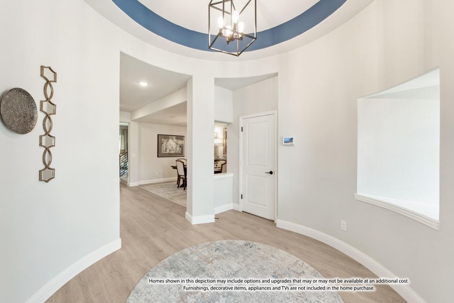 Foyer with round tray ceiling, blue accent, pendant light, and light wood floors opening to main living areas. Foyer with round tray ceiling, blue accent, pendant light, and light wood floors opening to main living areas.