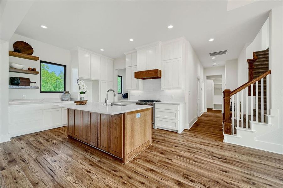 Kitchen featuring white cabinets, an island with sink, and light hardwood / wood-style floors