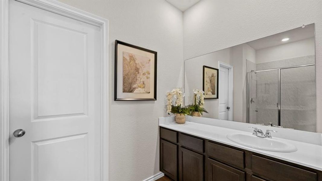 The bathroom features a vanity with a white countertop, an undermount sink, and a large mirror The bathroom features a vanity with a white countertop, an undermount sink, and a large mirror