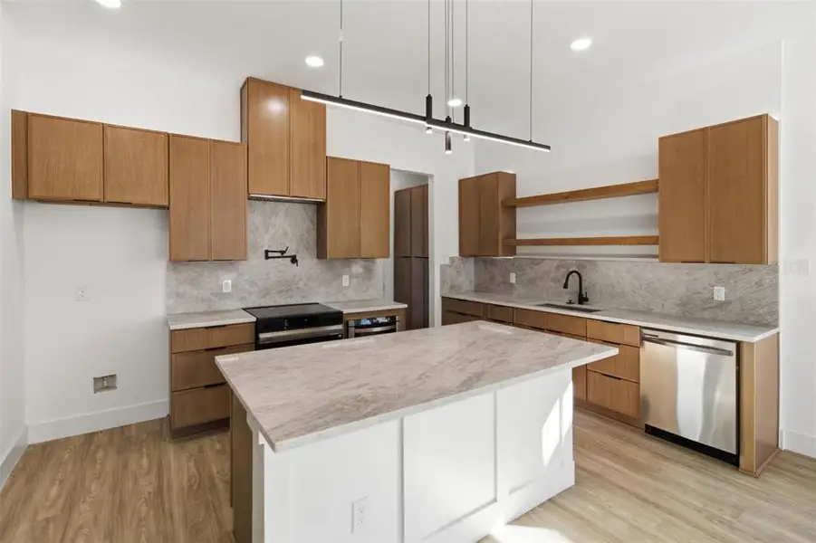 Kitchen featuring black / electric stove, dishwasher, tasteful backsplash, light wood finished floors, and two tone color scheme