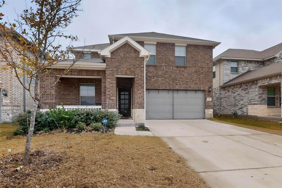 Traditional-style home featuring brick siding, concrete driveway, covered porch, and a garage Traditional-style home featuring brick siding, concrete driveway, covered porch, and a garage