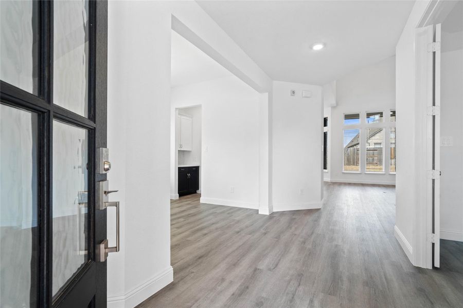 An inviting entrance opens up to an open-concept layout, seamlessly connecting the entry to the living areas with durable luxury vinyl plank flooring and striking architectural details.