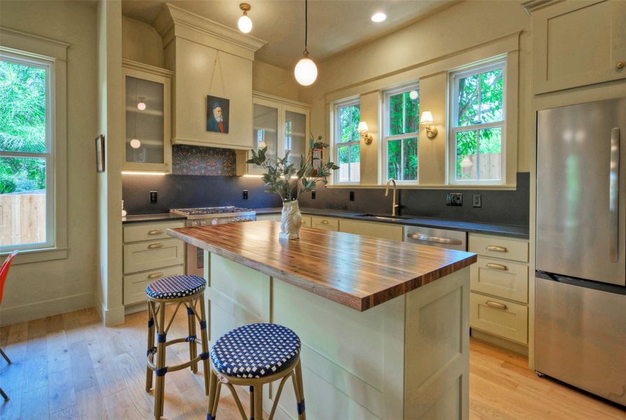A well-appointed kitchen features a butcher block island and light hardwood flooring.