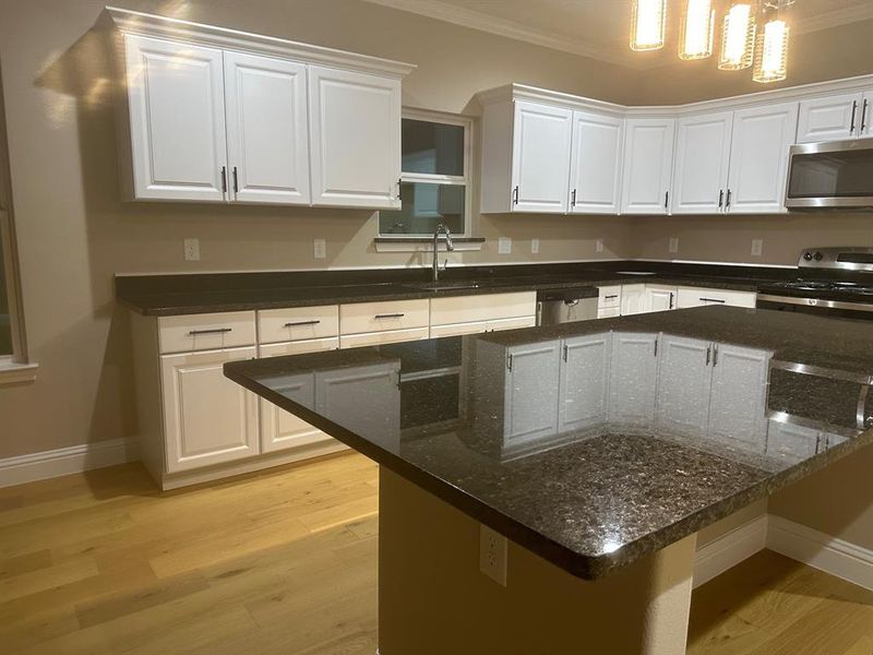 Kitchen with light wood-type flooring, white cabinetry, and appliances with stainless steel finishes