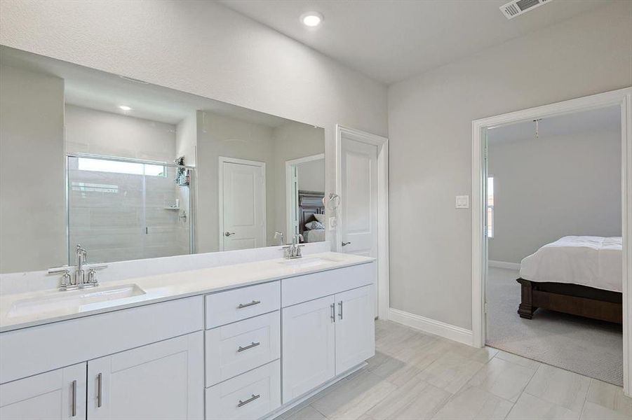 Bathroom featuring tile floors, an enclosed shower, and double sink vanity