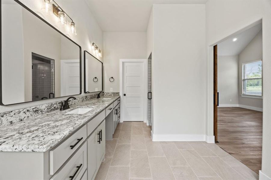 Bathroom with double vanity, light tile patterned floors, and a shower stall Bathroom with double vanity, light tile patterned floors, and a shower stall