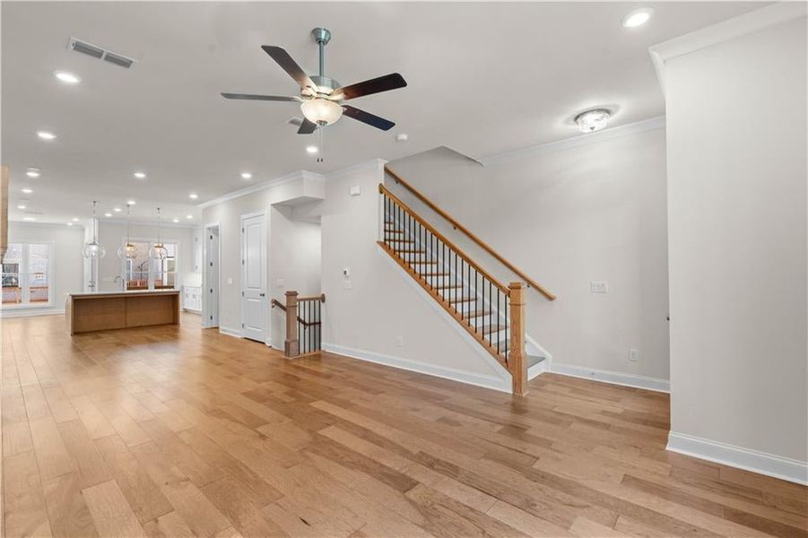 Unfurnished living room with recessed lighting, ornamental molding, stairway, light wood-style flooring, and ceiling fan