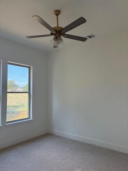 Carpeted spare room featuring baseboards and ceiling fan