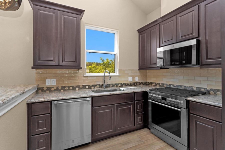 The guest home kitchen is beautifully appointed with rich cabinetry, granite countertops, a full suite of stainless appliances, and a scenic window above the sink. The guest home kitchen is beautifully appointed with rich cabinetry, granite countertops, a full suite of stainless appliances, and a scenic window above the sink.