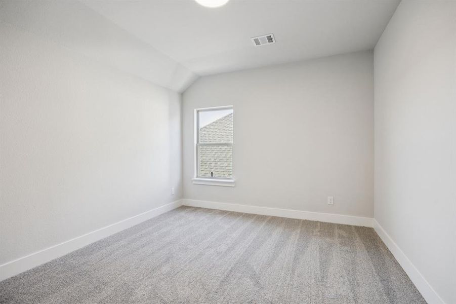 Unfurnished room featuring light carpet and vaulted ceiling