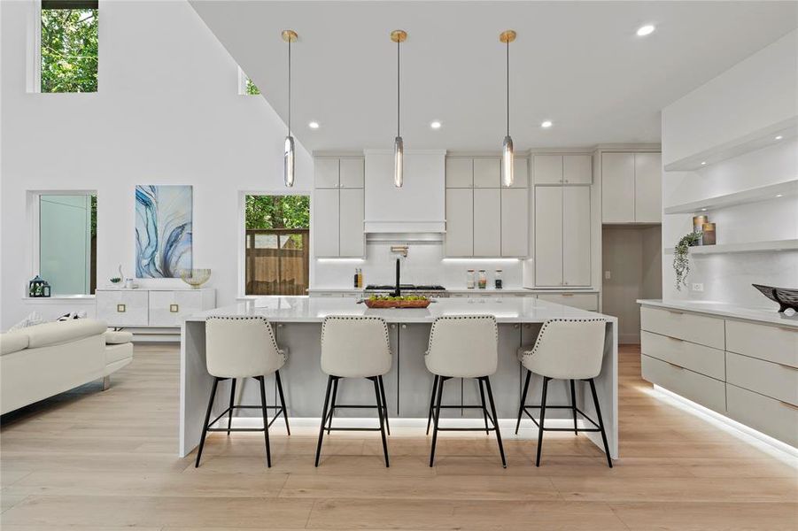 Kitchen with modern cabinets, white cabinetry, a kitchen bar, a large island with sink, and recessed lighting