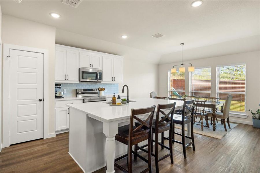 Kitchen with decorative backsplash, a breakfast bar area, stainless steel appliances, white cabinetry, and recessed lighting