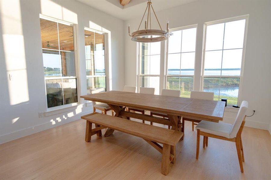 Dining room featuring a water view, light wood-style floors, and a chandelier Dining room featuring a water view, light wood-style floors, and a chandelier