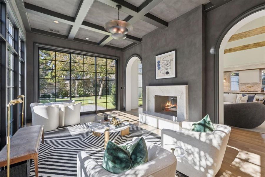Living room with a fireplace, beamed ceiling, coffered ceiling, wood finished floors, and arched walkways