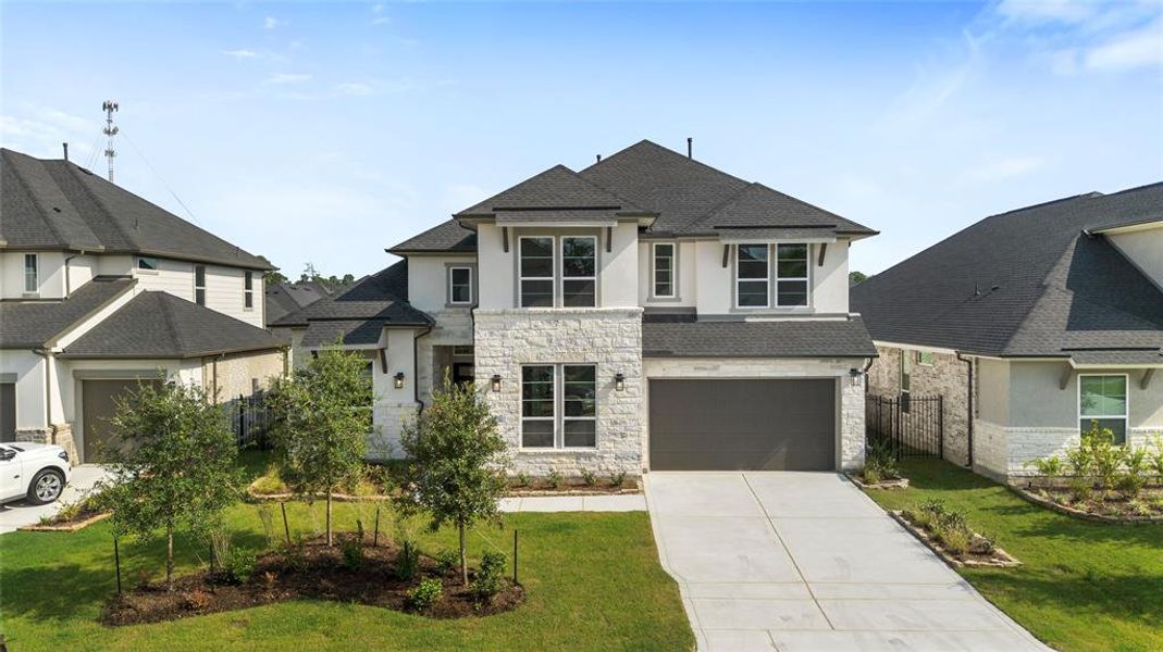 White stone facade with an ample driveway that enters into a 3 car garage