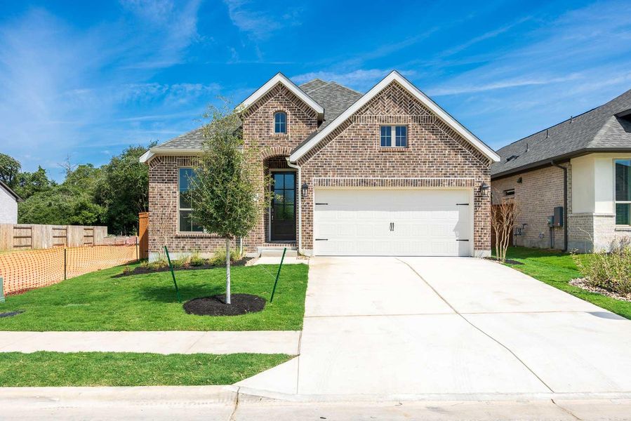 View of front of home with brick siding, concrete driveway, roof with shingles, and a garage