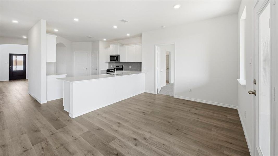 Kitchen with white cabinets, a peninsula, dark wood-style floors, arched walkways, and recessed lighting