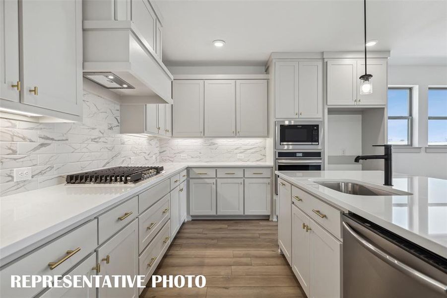 Beautiful cabinetry, gorgeous counter tops and designer backsplash effortlessly blend with contemporary stainless steel to create a kitchen for the ages!  REPRESENTATIVE PHOTO