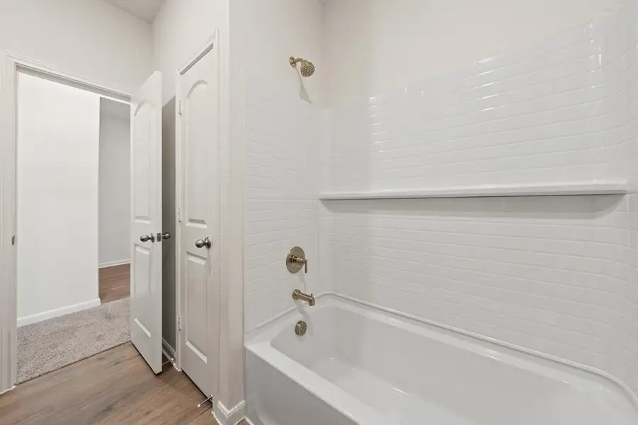 Bathroom with bathtub / shower combination and wood finished floors Bathroom with bathtub / shower combination and wood finished floors