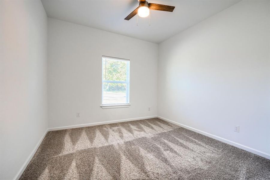 Carpeted spare room with baseboards and ceiling fan