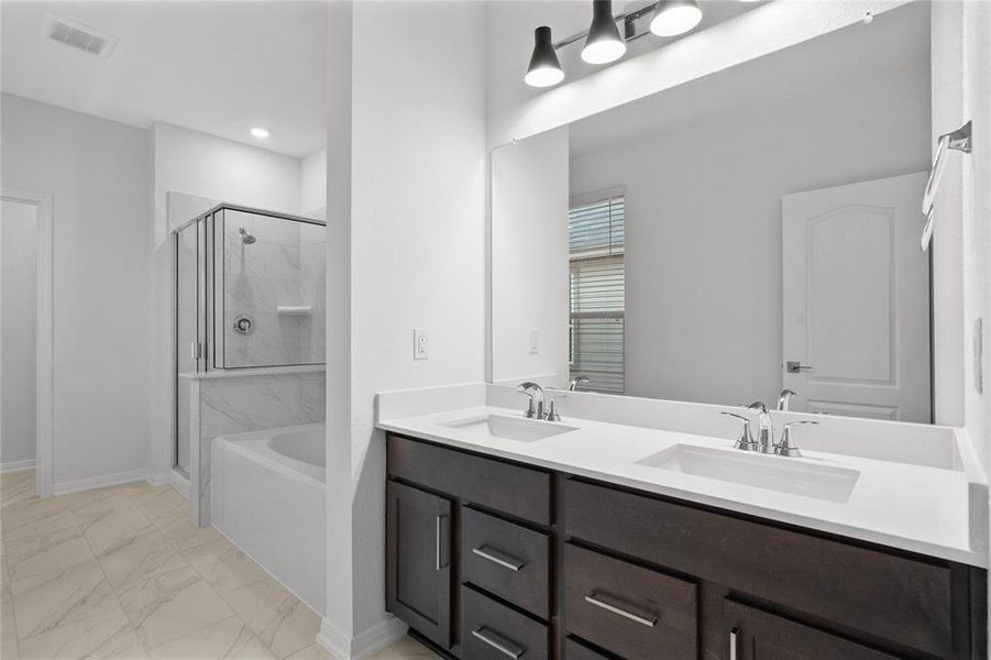 This primary bathroom is definitely move-in ready! Featuring an oversized tub and walk-in shower with tile surround, stained cabinets with light countertops, dual vanities, high ceilings, neutral paint, sleek and modern finishes.