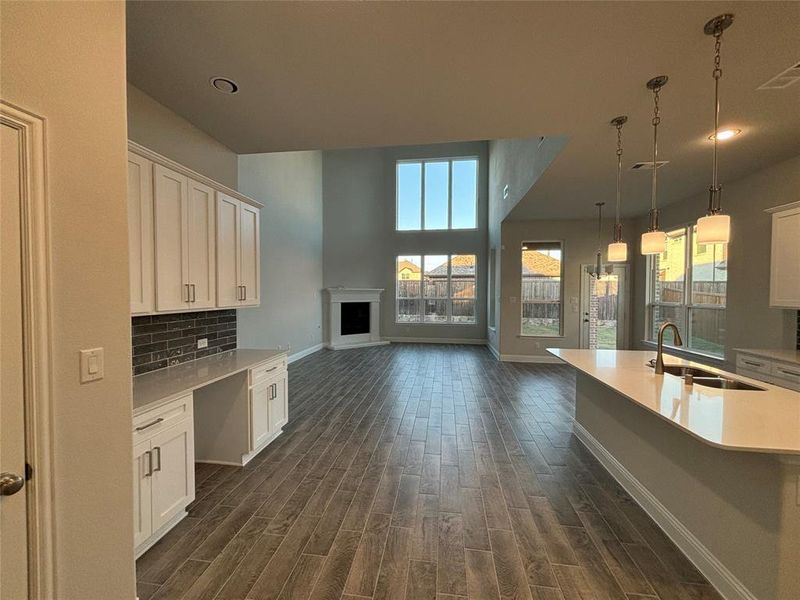 Kitchen featuring tasteful backsplash, sink, hanging light fixtures, white cabinetry, and dark hardwood / wood-style floors