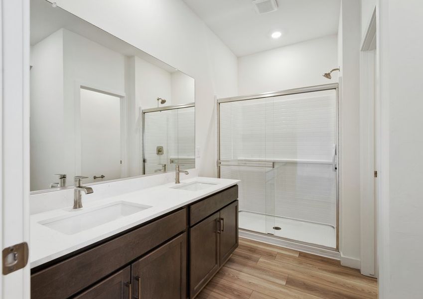 The master bathroom features a glass-enclosed shower and dual-vanity sinks.