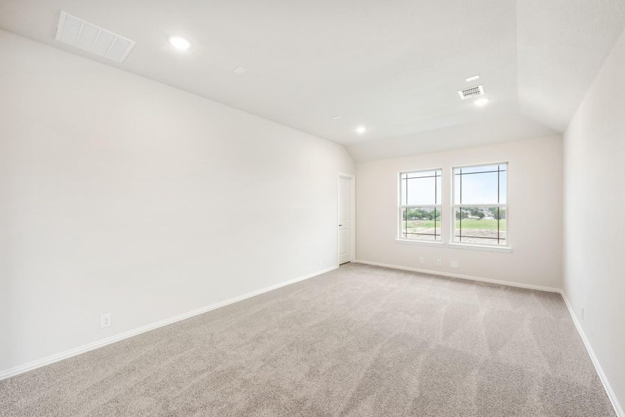 Empty bedroom with gray carpet, white walls, recessed lighting, and a large window with outdoor views Empty bedroom with gray carpet, white walls, recessed lighting, and a large window with outdoor views