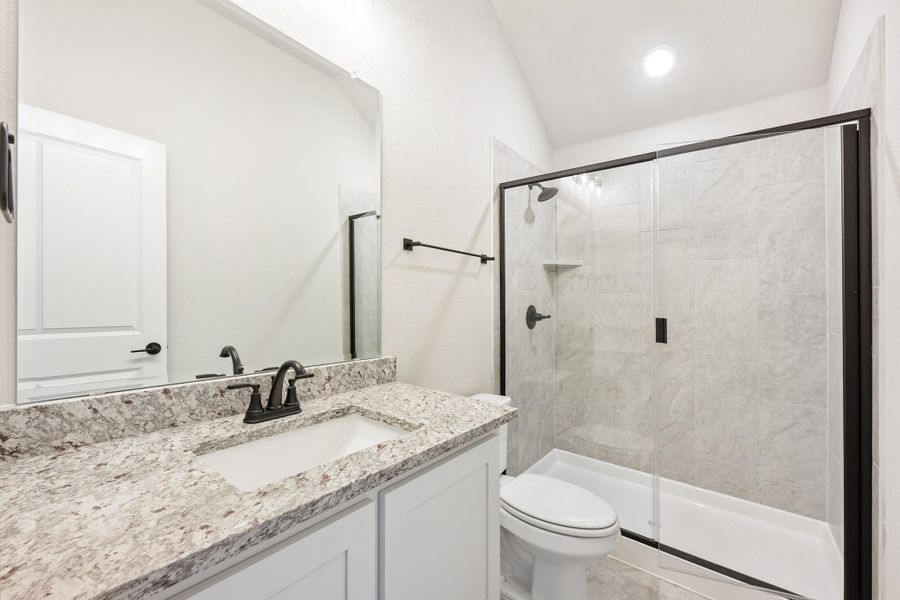 Bathroom with granite countertop vanity, glass-enclosed tile shower, and white toilet with dark bronze fixtures Bathroom with granite countertop vanity, glass-enclosed tile shower, and white toilet with dark bronze fixtures