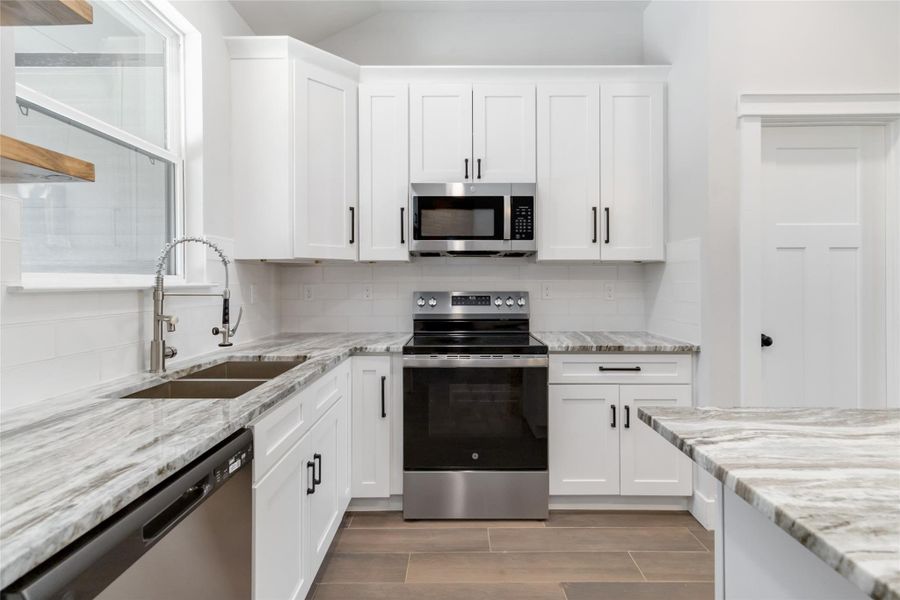 Kitchen featuring white cabinets, appliances with stainless steel finishes, sink, and backsplash