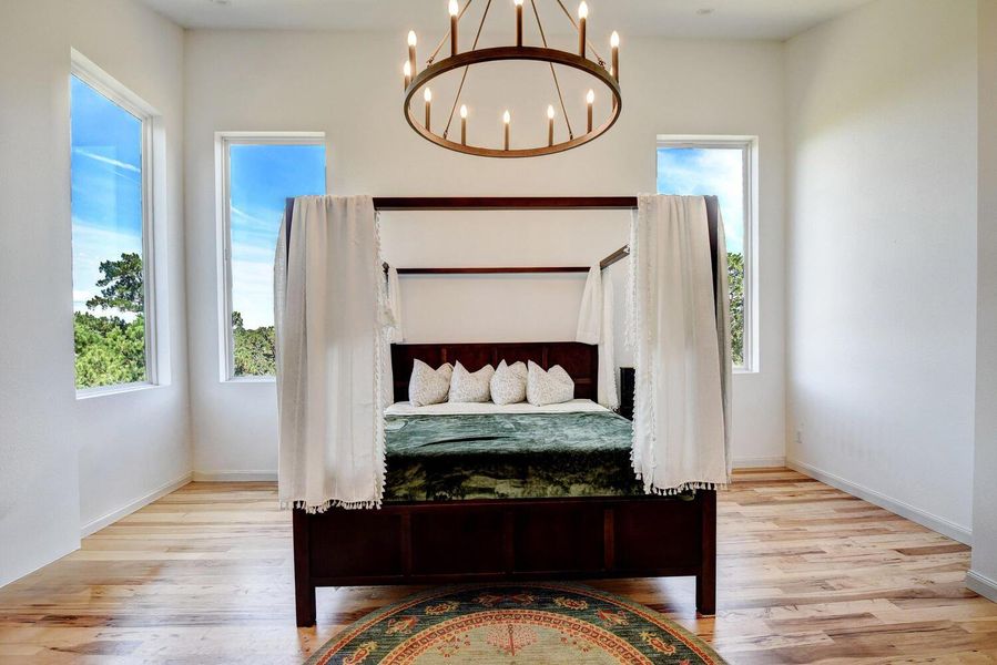 Bedroom with light wood-type flooring and a chandelier Bedroom with light wood-type flooring and a chandelier