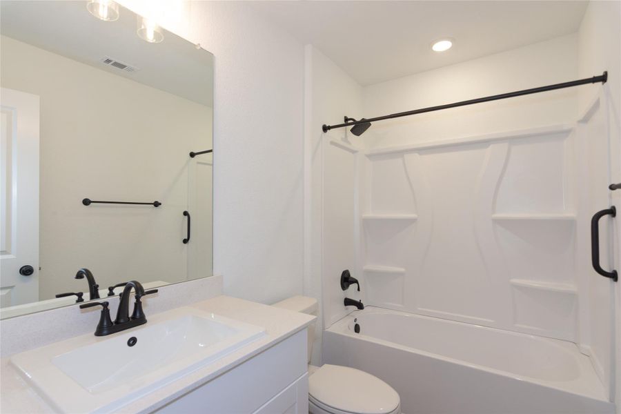 Bathroom featuring a white vanity with an integrated sink, matte black faucet, and a large mirror