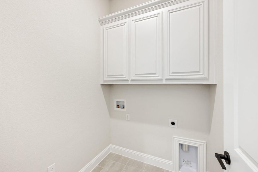 Laundry room with white upper cabinets, washer and dryer hookups, and tile flooring Laundry room with white upper cabinets, washer and dryer hookups, and tile flooring