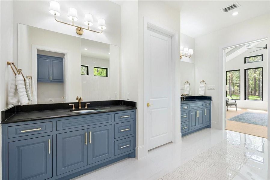The primary bath pairs soapstone surfaces, custom cabinetry, and a freestanding soaking tub to create a private retreat that feels calm, indulgent, and deeply personal.