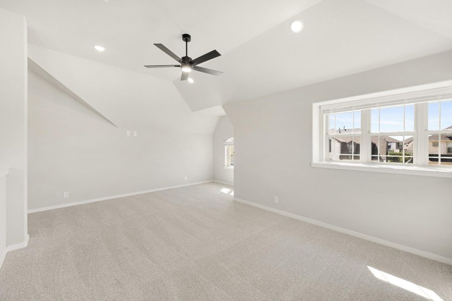Empty bedroom with vaulted ceiling, ceiling fan, carpet flooring, and large window