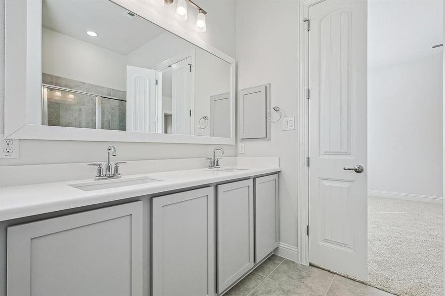 Bathroom with tile patterned flooring, a shower with shower door, and vanity