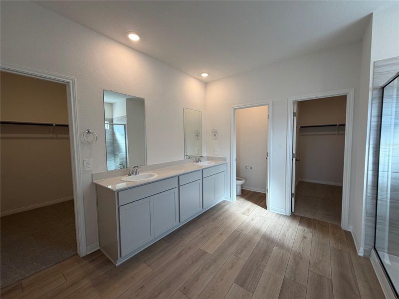 Full bath featuring a spacious closet, a shower stall, and double vanity