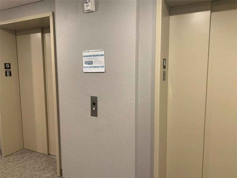 Elevator featuring a textured wall and carpet flooring