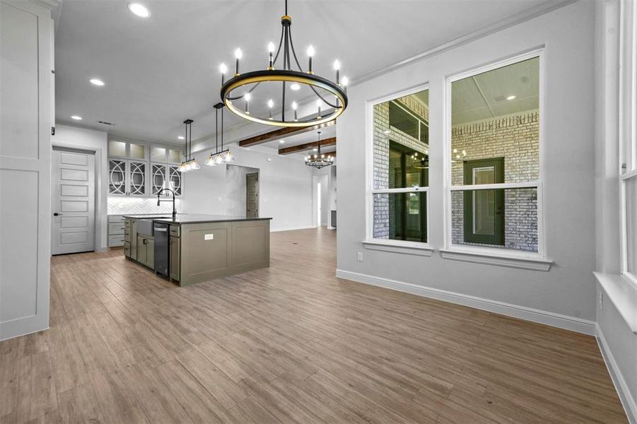 Kitchen featuring a kitchen island with sink, sink, wood-type flooring, decorative light fixtures, and an inviting chandelier