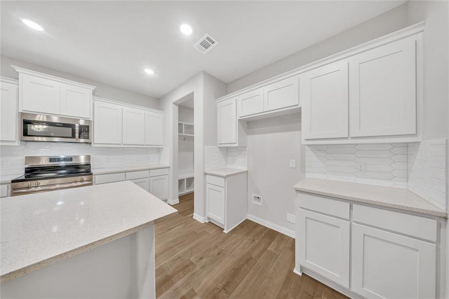 Kitchen featuring stainless steel appliances, tasteful backsplash, light wood finished floors, white cabinets, and recessed lighting Kitchen featuring stainless steel appliances, tasteful backsplash, light wood finished floors, white cabinets, and recessed lighting
