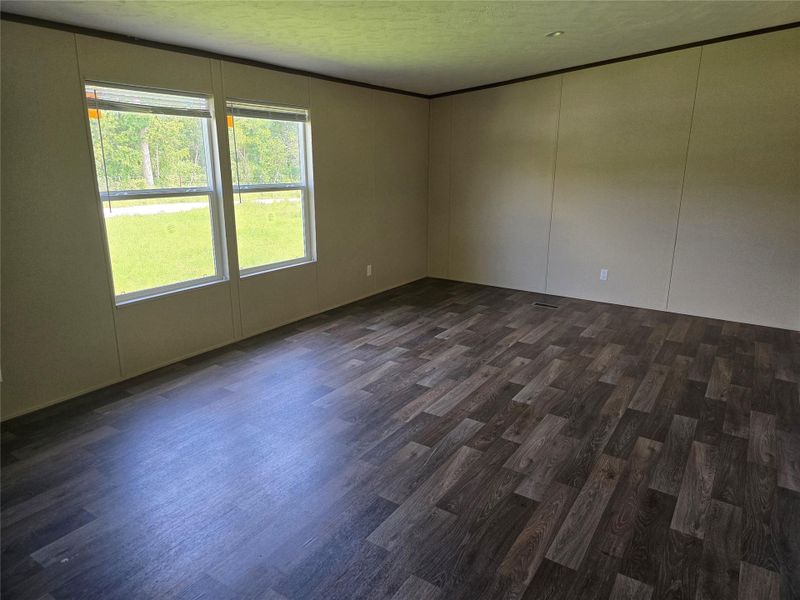 Spacious room featuring wood-finish flooring, light-toned walls, and dark trim Spacious room featuring wood-finish flooring, light-toned walls, and dark trim