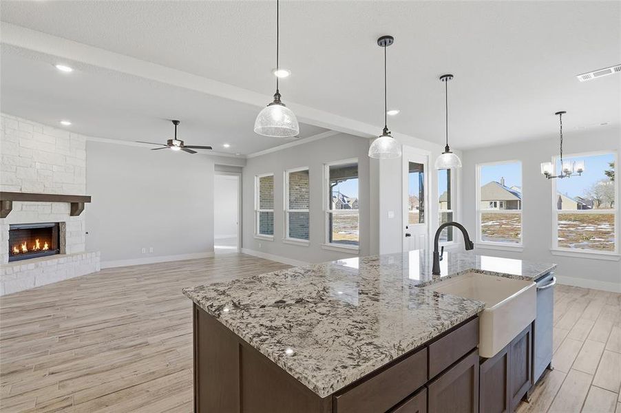 Kitchen with dark brown cabinetry, hanging light fixtures, light wood-style flooring, open floor plan, and recessed lighting