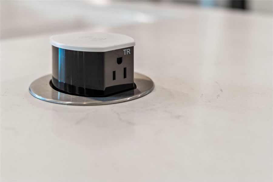 This sleek, pop-up electrical receptacle is a standout functional feature of the modern kitchen island, designed to keep the workspace clean and uncluttered.