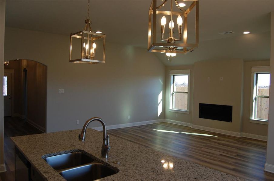 Kitchen featuring a wealth of natural light, dark wood-type flooring, sink, and light stone countertops