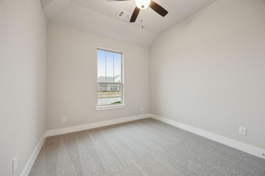 Empty room featuring ceiling fan, lofted ceiling, and carpet