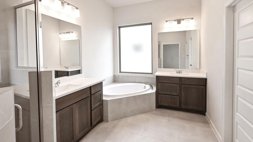 Bathroom featuring a bath, two vanities, light tile patterned floors, and a stall shower